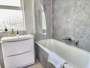 a bathroom with a white tub and a sink and a window at 4Bedroom Modern Bicester Villa, WIFI, Parking, Garden, Minutes walk to Bicester Village in Bicester