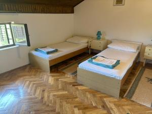 two twin beds in a room with wooden floors at Apartments Radulović in Biograd na Moru