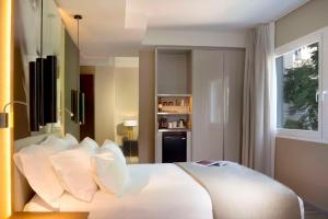 a bedroom with a large bed with white pillows at NH Collection Madrid Suecia in Madrid