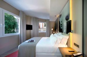 a hotel room with a large white bed and a desk at NH Collection Madrid Suecia in Madrid