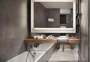a bathroom with a sink and a mirror and a tub at NH Collection Madrid Suecia in Madrid