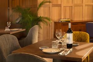 a bottle of wine on a wooden table with glasses at NH Collection Madrid Suecia in Madrid