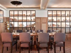a dining room with a table and chairs and windows at NH Collection Madrid Suecia in Madrid