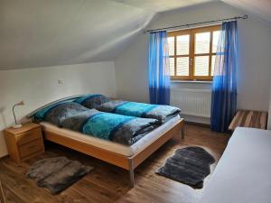 a bedroom with a bed with blue curtains and a window at Ferienwohnung "Kräuterhof" in Ringelai