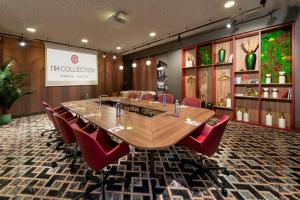 a conference room with a long table and red chairs at NH Collection Madrid Suecia in Madrid