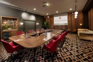 a conference room with a long table and red chairs at NH Collection Madrid Suecia in Madrid