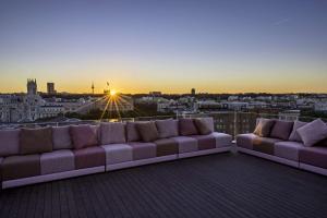 a couch sitting on top of a balcony with the sunset at NH Collection Madrid Suecia in Madrid