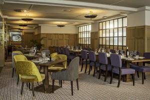 a dining room with tables and chairs and windows at NH Collection Madrid Suecia in Madrid