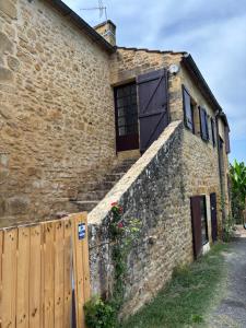 a brick house with a wooden gate and stairs at Corps de ferme rénové à 10 min de Sarlat in Carsac-Aillac