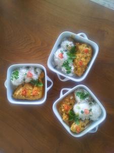 three dishes of food with rice and broccoli on a table at CoCoKreyol - " GRENADINE " in Les Trois-Îlets