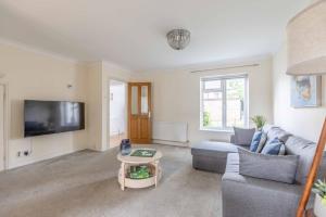a living room with a couch and a tv at Spacious 4-Bedroom Home - Parking - Garden in White Waltham