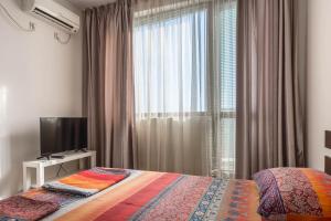 ein Schlafzimmer mit einem Bett, einem Fernseher und einem Fenster in der Unterkunft FANTASY APARTMENTS in Warna