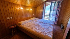 a bed in a wooden room with a window at Chalet Lu Verzache 5 personnes in Evolène