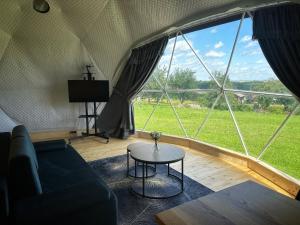 a living room with a large window with a couch and a table at Osada przy Szlaku Glamping Ojców in Wola Kalinowska