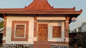 a small house with a red roof and wooden doors at Naufal homestay & kost in Ngemplak