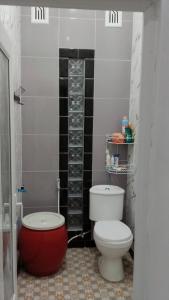 a bathroom with a white toilet and a red tub at Naufal homestay & kost in Ngemplak