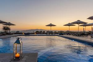 a pool with umbrellas and a candle next to it at Evripus Suites in Kastraki Naxou
