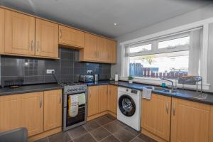 a kitchen with wooden cabinets and a washing machine at Free Parking - Central - Sleeps 6 - 2 Bedrooms in Livingston