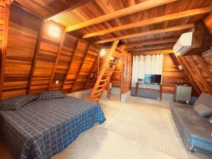 a bedroom with wooden walls and a bed and a television at Chalé Toledo e Costa II in Itapeva