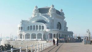 a large white building with people standing in front of it at To the Nerversea beach! in Constanţa