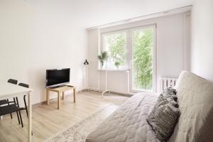 a white living room with a couch and a television at Apartamenty Trójmiejskie - Sopot Forest 2 Bedroom in Sopot