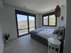 a bedroom with a bed and a table and windows at Villa Zina mit Infinity-Pool und Meerblick in Sitia