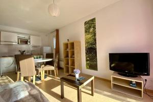 a living room with a flat screen tv and a table at Les Naïades I55 - 2 bedroom for 4 people in Avène