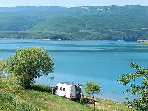 ein Wohnmobil, das am Ufer eines Sees geparkt ist in der Unterkunft Kamp Markešić in Šćit