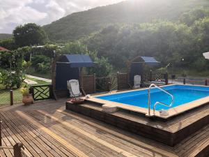 a swimming pool on a wooden deck next to a mountain at Aichi's lodges -gîtes in Capesterre