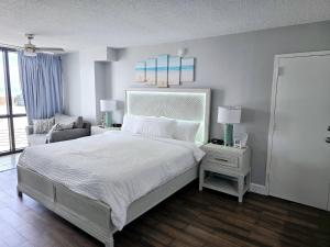 a bedroom with a white bed and a chair at Oceanview 2 Studios adjoining w/pool, kitchenettes in Daytona Beach +39 photos