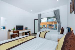 Resort Mini Mới Khai Trương في فنغ تاو: سريرين في غرفة مع مكتب وتلفزيون