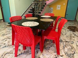 a black table and red chairs in a room at ALOamarALO - Homely Comfort with a Touch of Luxury at Shantiniketan in Shānti Niketan