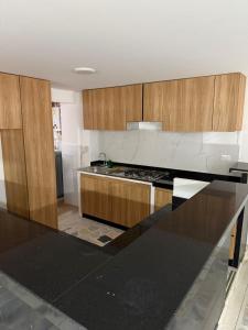 eine Küche mit Holzschränken und einer schwarzen Arbeitsplatte in der Unterkunft Apartamento en Paipa - Boyacá in Paipa