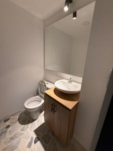 ein Badezimmer mit Toilette, Waschbecken und Spiegel in der Unterkunft Apartamento en Paipa - Boyacá in Paipa
