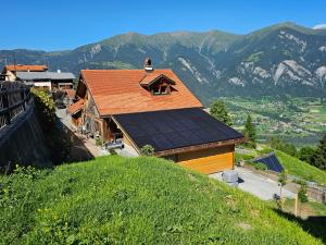 a house with a roof on top of a hill at Försterhaus Dalin Ferienwohnung Schweizer Alpen in Präz