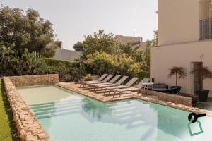 a swimming pool with lounge chairs next to a house at HOTIDAY Mondello Beach in Mondello