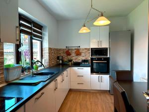 a kitchen with white cabinets and a black counter top at Holiday Home ESKU in Orşova