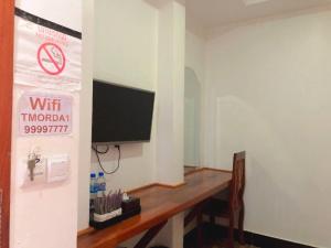 a room with a table and a television on a wall at Thmor Da Guest House in Kampong Cham