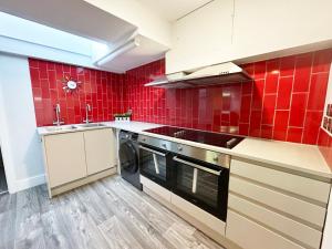 eine rot geflieste Küche mit einer Spüle und einem Geschirrspüler in der Unterkunft Maidstone House Kent By Smart Corporate Stays in Maidstone + 8 Fotos