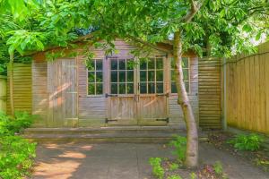 eine Holzhütte mit einer Tür und einem Baum in der Unterkunft Maidstone House Kent By Smart Corporate Stays in Maidstone