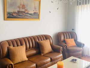 a living room with a brown couch and a chair at Refugio Terrace House Peniche in Atouguia da Baleia +15 photos