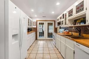 une grande cuisine avec des armoires blanches et un réfrigérateur dans l'établissement The Cozy Cottage Getaway - Private Pool & Hot Tub, à Kirbyville