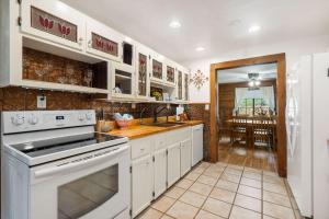 une cuisine avec des armoires blanches et un four à plaques de cuisson dans l'établissement The Cozy Cottage Getaway - Private Pool & Hot Tub, à Kirbyville 17 autres photos
