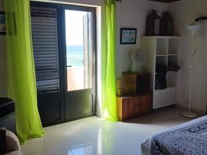 a bedroom with green curtains and a door with a view at Casa da Torre Rooftop Terrace in Praia da Areia Branca