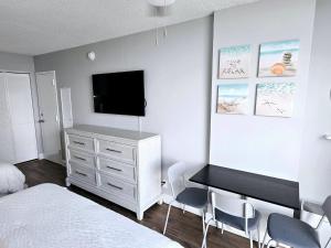 デイトナビーチにあるNew updated Daytona Oceanview w/kitchenette, poolのベッドと壁掛けテレビのある寝室