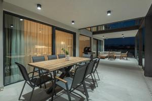 a dining room with a wooden table and chairs at Seafront Villa Serena with pool and seaview in Privlaka