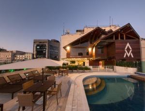 a hotel with a pool and tables and chairs at Studio ao lado do Museu do Amanhã in Rio de Janeiro
