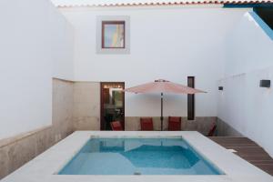 a swimming pool with an umbrella and a table with an umbrella at GinHouses Casa do Outeiro - Porto da Espada, Marvão in Marvão