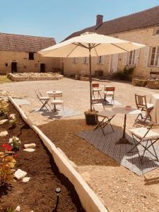 StignyにあるLe domaine aux herbes follesのテーブルと椅子と傘のあるパティオ