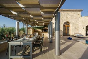 an outdoor dining area with a table and chairs at Spacious Stone Villa with Private Pool, Sea View & Sunset Views in Astérion